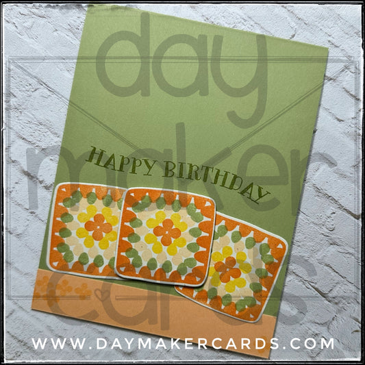 Handmade birthday card with granny square designs and 'Happy Birthday' text on a soft green background, featuring Day Maker Cards branding.
