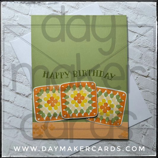 Handmade birthday card with granny square designs and 'Happy Birthday' text on a soft green background, featuring Day Maker Cards branding.