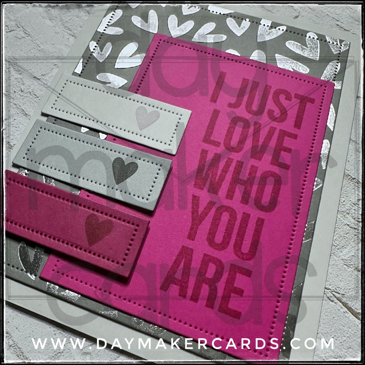 Detailed image of a handmade card from Day Maker Cards, stamped with 'I Just Love Who You Are' text on a pink background and die-cut details featuring small pierced holes.