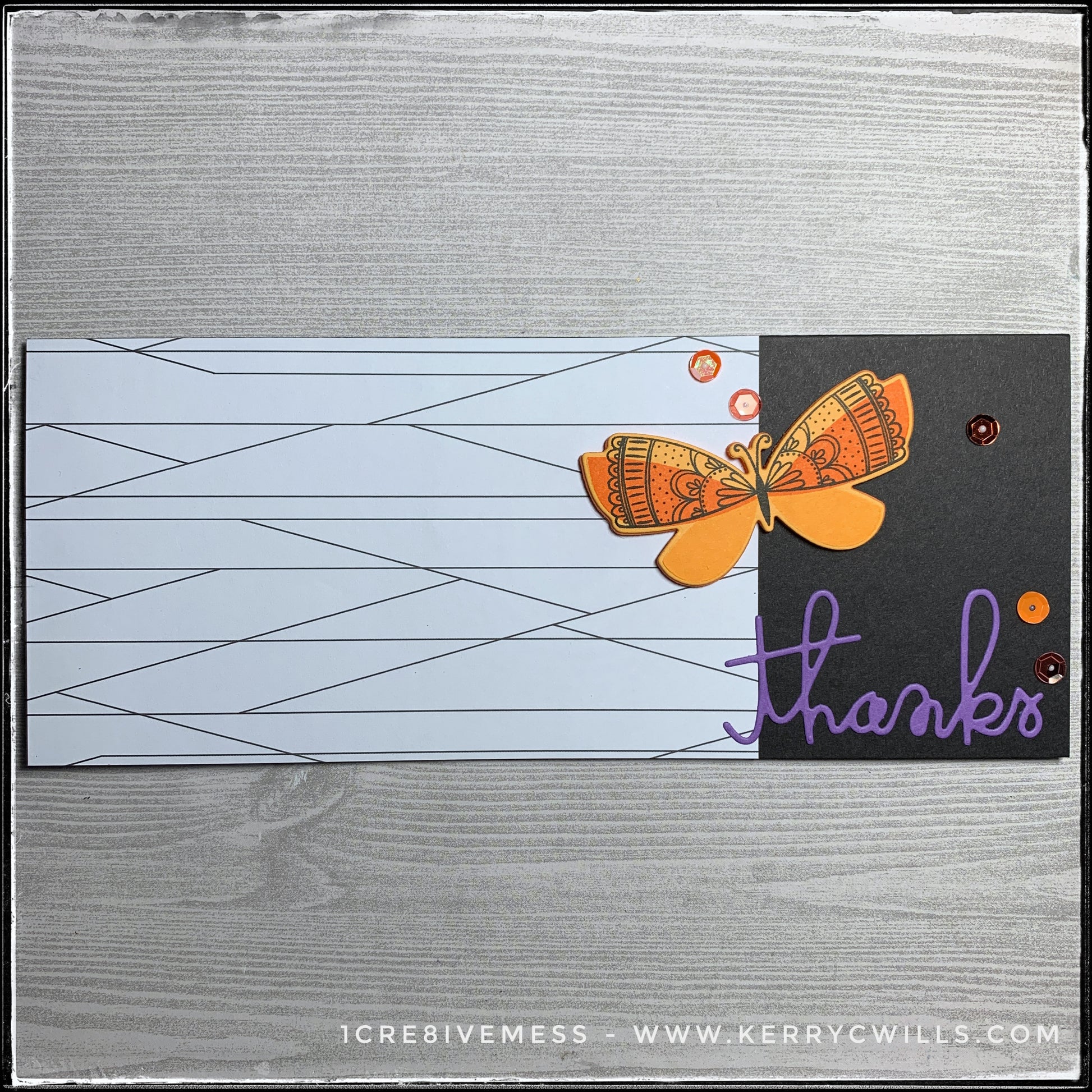 A flat-lay view of this thank you slimline handmade card. The left side features white paper with a thin black line pattern that butts up against the black card base. Near the bottom right is the die-cut word "thanks" which is cut from purple cardstock. An orange butterfly has been stamped and die-cut out of both cardstock and fun foam for added dimension. A smattering of sequins in a variety of shades of orange accent the right side of the handmade card. 