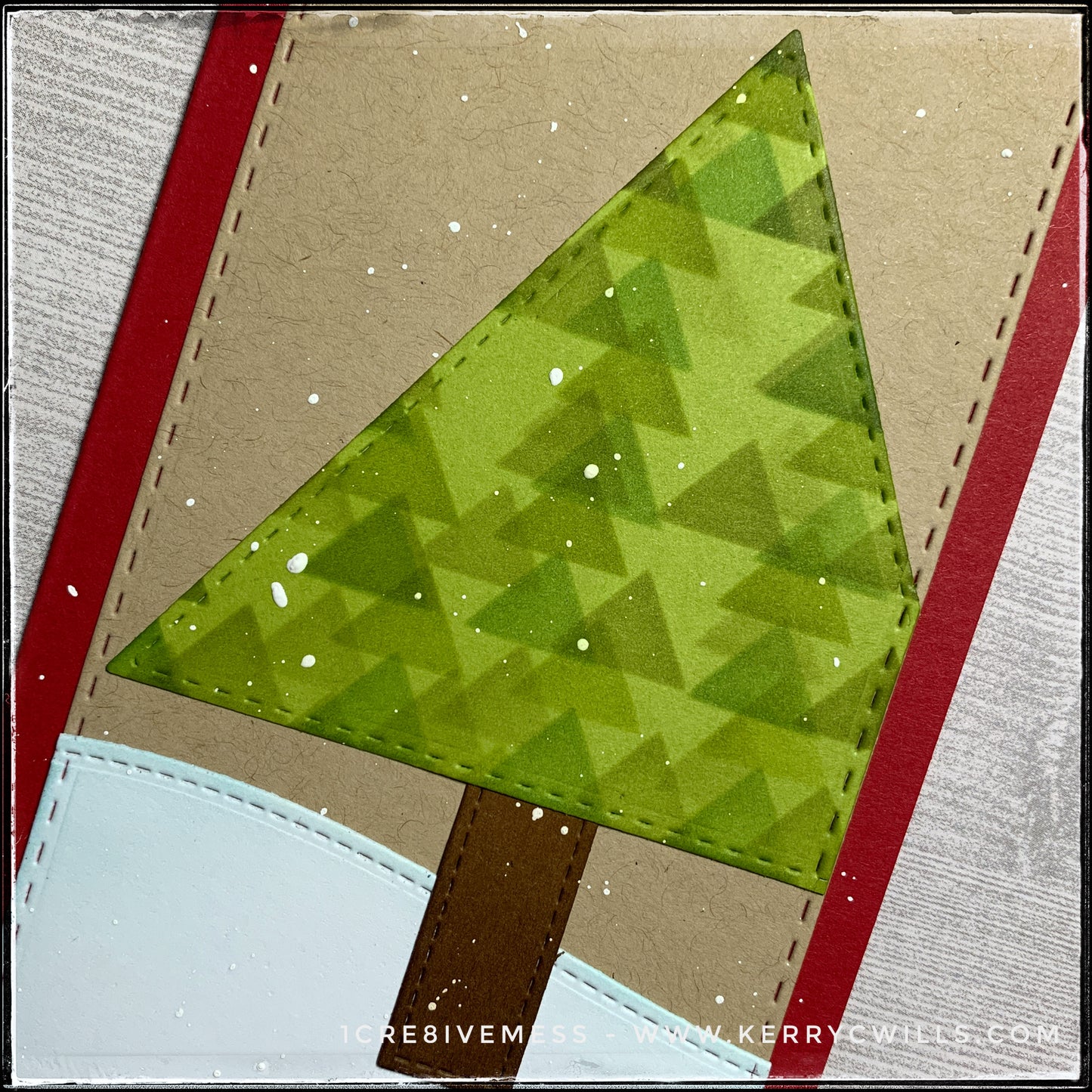 An angled flat-lay of the card front, focusing on the detail on the holiday tree created from a die-cut triangle, stenciled with overlapping smaller triangles in shades of green ink. The edges of the tree and the tree trunk coordinate with the edges of the card front panel - all with faux stitched detail. 