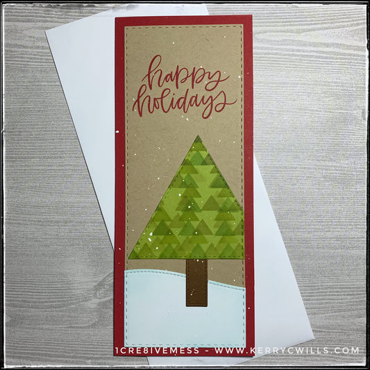 A vertical style slimline card, the stamped sentiment on this reads "happy holidays" in red ink in a scripty font near the top of the card. Faux stitched detail is evident all around the edges of this front card panel, as well as on the details. There's a die-cut triangle which creates a tree and has been stenciled with a repeating pattern of triangles in shades of green. A snowdrift grounds the tree near the bottom of the card. White flecks of paint are scattered across the card front to look like snow.